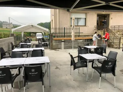 a group of tables and chairs in a patio at Pensión Tasaga in O Pino