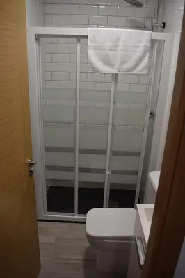 a bathroom with a toilet and a window with a towel at Pensión Tasaga in O Pino