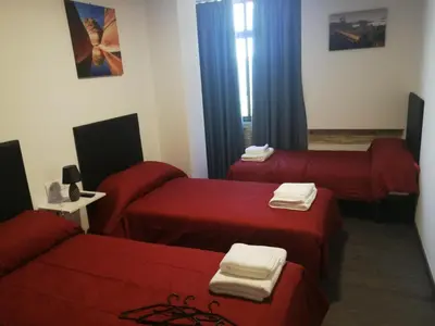 a room with three beds with red sheets at Pensión Tasaga in O Pino
