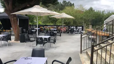 a group of tables and chairs with umbrellas at Pensión Tasaga in O Pino