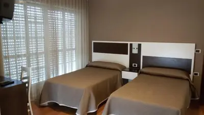 a bedroom with two beds and a window at Hotel El Millón in Viveiro