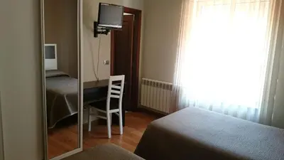 a mirror in a room with a bed and a chair at Hotel El Millón in Viveiro