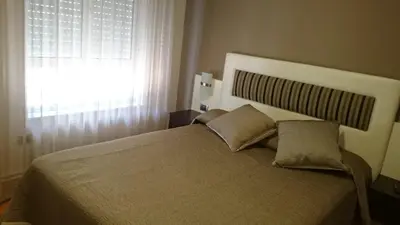 a bedroom with a bed with two pillows and a window at Hotel El Millón in Viveiro