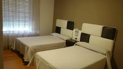 a hotel room with two beds and a window at Hotel El Millón in Viveiro
