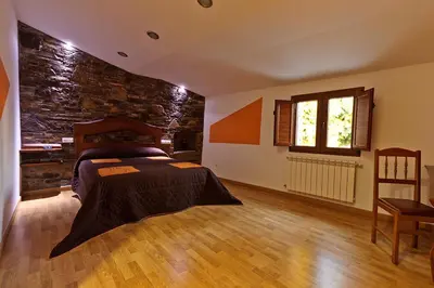 a bedroom with a bed and a stone wall at Casa Cazoleiro in Meira