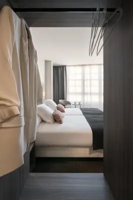 a bedroom with a large bed with white sheets and pillows at Hostal Pórtico in Betanzos