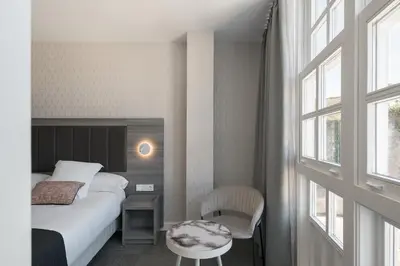 a bedroom with a bed and a table and a window at Hostal Pórtico in Betanzos