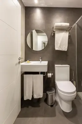 a bathroom with a sink and a toilet and a mirror at Hostal Pórtico in Betanzos