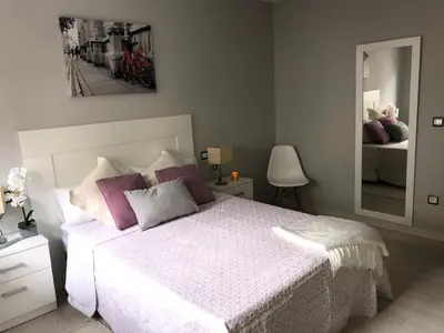 a bedroom with a white bed with purple pillows and a mirror at Apartamento Adelina in Silleda