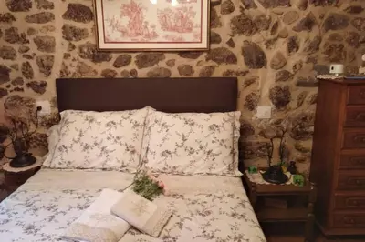 a bed in a room with a stone wall at Casa Cabaleira in Silleda