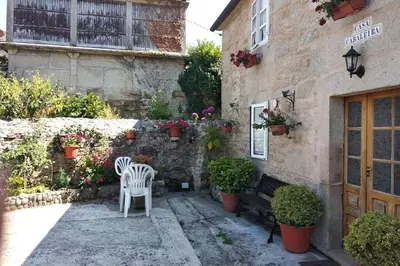 a patio with two white chairs and a building at Casa Cabaleira in Silleda