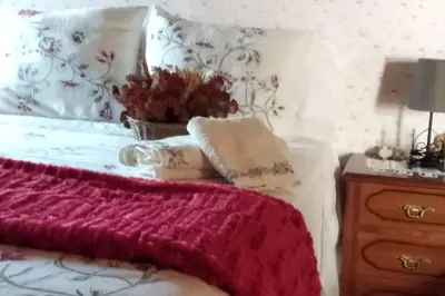 a bed with a red blanket and a table with a lamp at Casa Cabaleira in Silleda