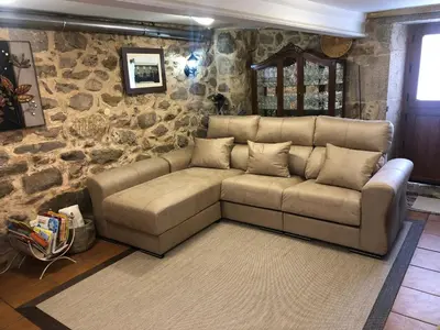 a living room with a couch and a stone wall at Casa Cabaleira in Silleda