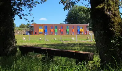 a bench in front of a building with colorful doors at CELTAINER in Maceda