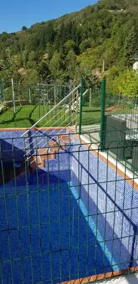 a large swimming pool with blue water and a fence at Hotel Alina in Cangas del Narcea