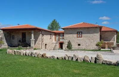 a large stone house with a grass yard in front of it at Casa Rural Rectoral Santa Baia in Boimorto