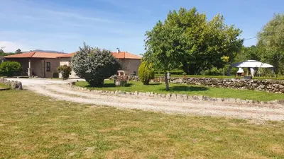 a dirt road in front of a house with a stone wall at Casa Rural Rectoral Santa Baia in Boimorto