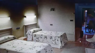 a room with two beds and a table in it at Casa Rural Rectoral Santa Baia in Boimorto