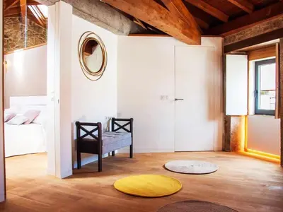 a living room with a chair and a yellow rug at A Forxa - Casa Ferrador (Ribeira Sacra) in Sober