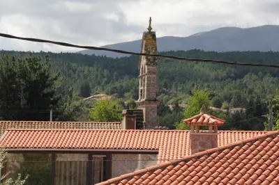 a building with a clock tower in the distance with a roof at A Forxa - Casa Ferrador (Ribeira Sacra) in Sober