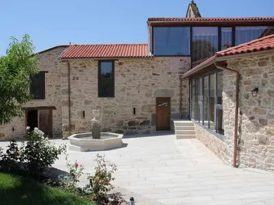 a stone house with a courtyard with a fountain at A Forxa - Casa Ferrador (Ribeira Sacra) in Sober