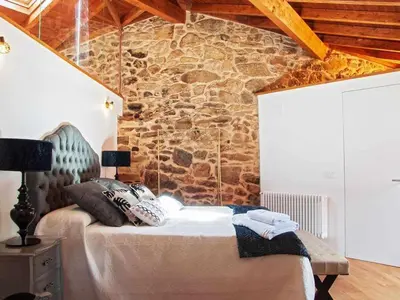a bedroom with a bed with a stone wall at A Forxa - Casa Ferrador (Ribeira Sacra) in Sober