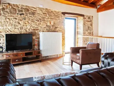 a living room with a couch and a television at O Forno - Casa Ferrador (Ribeira Sacra) in Sober