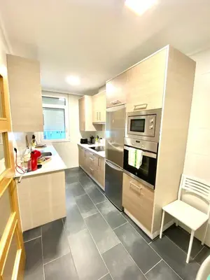 a kitchen with stainless steel appliances and wooden cabinets at ARENAL HOME, PARKING GRATIS in Lugo