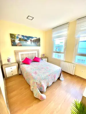 a bedroom with a bed with two red pillows at ARENAL HOME, PARKING GRATIS in Lugo