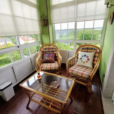 two chairs and a coffee table in a room with windows at O Seixo 2 in Mugardos
