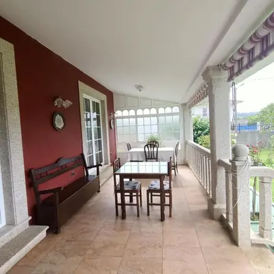 a dining room with a table and chairs on a porch at O Seixo 2 in Mugardos