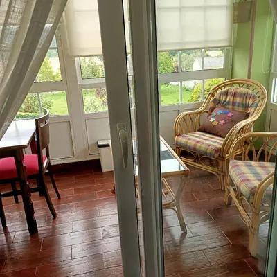 a living room with chairs and a table and windows at O Seixo 2 in Mugardos