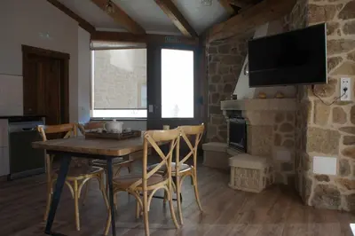 a kitchen and dining room with a wooden table and chairs at O Muiño - Casa Ferrador (Ribeira Sacra) in Barantes