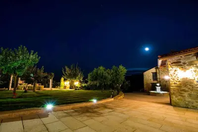 a night view of a yard with a building with lights at O Muiño - Casa Ferrador (Ribeira Sacra) in Barantes