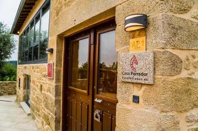 a stone building with a door and a sign on it at O Muiño - Casa Ferrador (Ribeira Sacra) in Barantes
