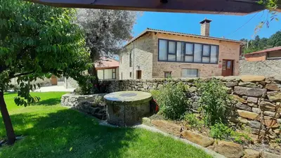 a stone house with a stone wall and a stone bench at O Muiño - Casa Ferrador (Ribeira Sacra) in Barantes