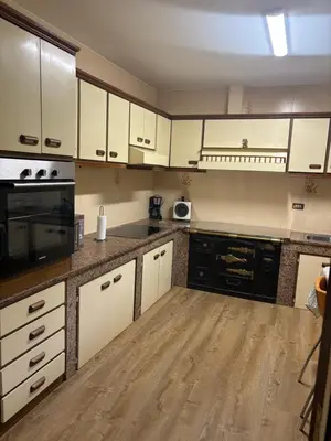 a kitchen with white cabinets and a wooden floor at Casa Hipólito in A Estrada
