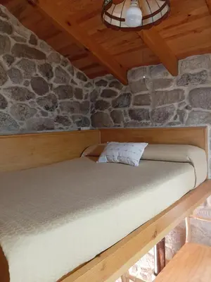 a bed in a room with a stone wall at Casa da mestre in Crecíente