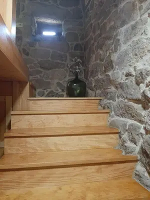 a set of wooden stairs with a stone wall at Casa da mestre in Crecíente