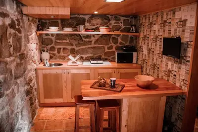 a kitchen with a wooden table and a stone wall at Casa da mestre in Crecíente