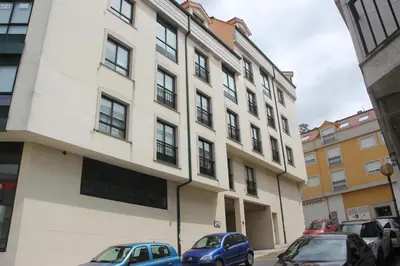 a building with cars parked in front of it at Piso céntrico en Miño. in Miño