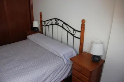 a bedroom with a bed and a nightstand with two lamps at Piso céntrico en Miño. in Miño