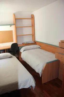 two beds in a room with wooden floors at Piso céntrico en Miño. in Miño