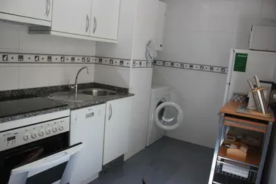 a white kitchen with a sink and a washing machine at Piso céntrico en Miño. in Miño