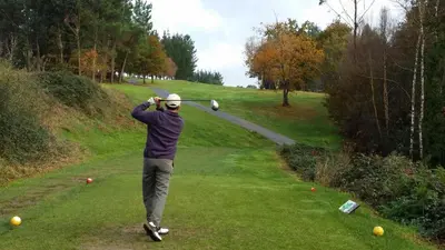 a man swinging a golf club on a golf course at Piso céntrico en Miño. in Miño