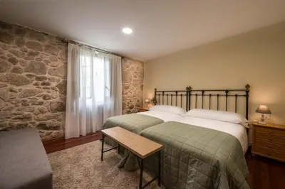 a bedroom with two beds and a stone wall at Aldeade in Ferreira de Panton