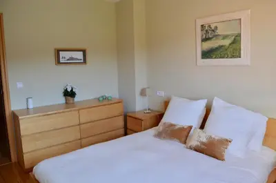 a bedroom with a white bed and a dresser at Precioso adosado en Urbanización con campo de golf in Miño
