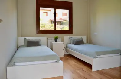 two beds in a room with a window at Precioso adosado en Urbanización con campo de golf in Miño