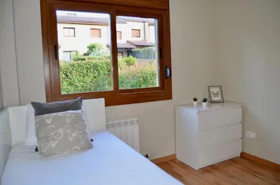 a bedroom with a white bed and a window at Precioso adosado en Urbanización con campo de golf in Miño