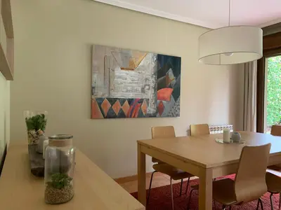 a dining room with a table and a painting on the wall at Precioso adosado en Urbanización con campo de golf in Miño
